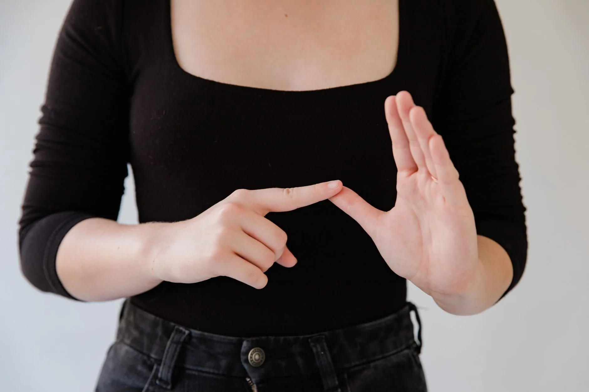 Personne en haut noir faisant un geste de langue des signes avec les mains